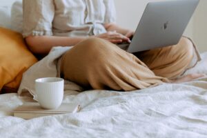 Persona relajada trabajando en una laptop en un ambiente hogareño, reflejando habilidades blandas intrapersonales como la autodisciplina.