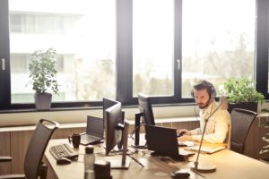 Empleado de servicio al cliente concentrado en su trabajo con auriculares, ejemplificando habilidades blandas en un entorno de oficina iluminado.