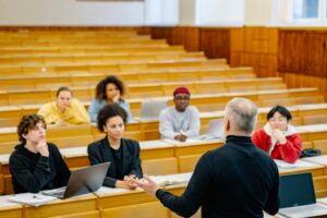 Un profesor interactuando con estudiantes en una aula universitaria