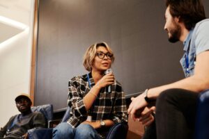 Una mujer con micrófono participa activamente en una discusión de grupo, ejemplificando habilidades de comunicación y liderazgo destacadas en LinkedIn.