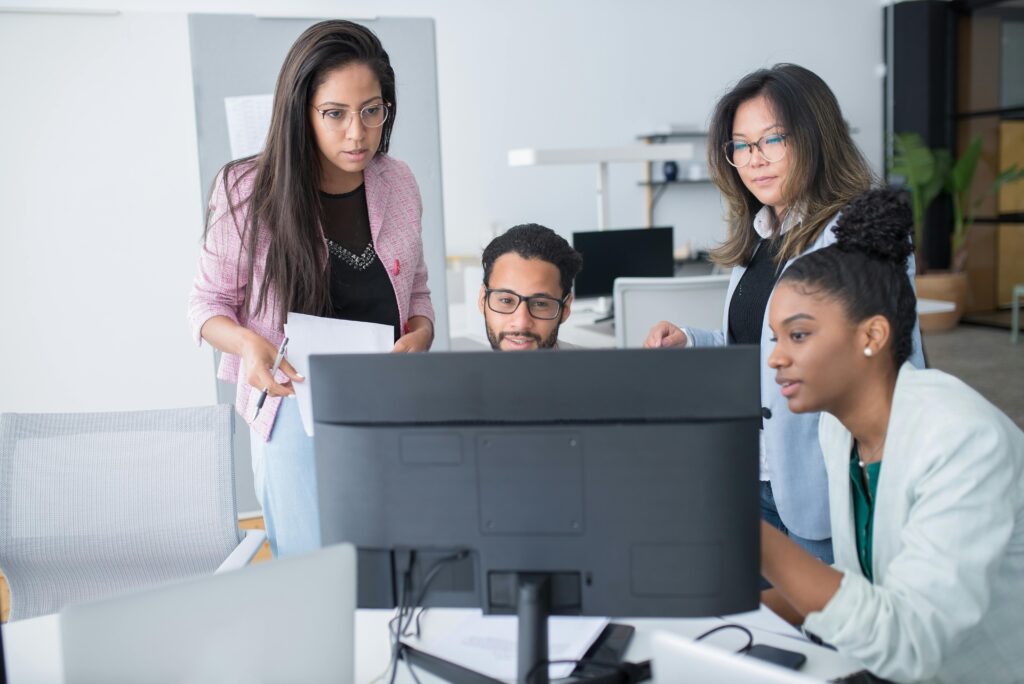 Un equipo diverso de cuatro profesionales analiza datos en la pantalla de un ordenador, reflejando las habilidades blandas más demandadas en el mercado laboral futuro.